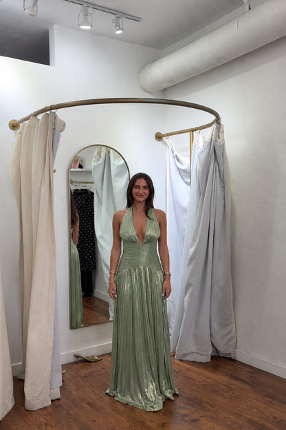 Front view of model wearing sage green metallic pleated halter maxi evening gown